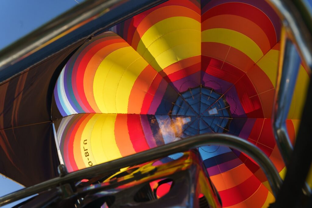 kleurige luchtballon in opblaasfase gezien vanuit mand met vlam in beeld comfort ballonvaarten airo west-vlaanderen henegouwen
