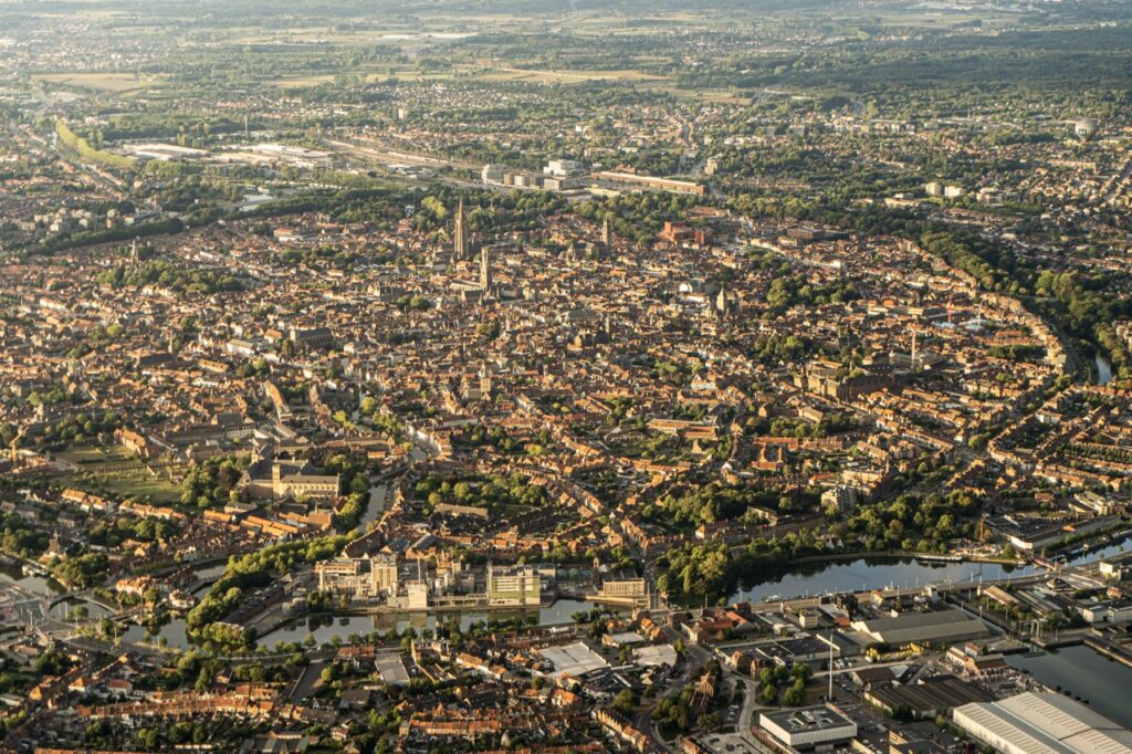 luchtfoto van bruisend stadscentrum met historische gebouwen en kanalen in West-Vlaanderen met Airo ballonvaarten