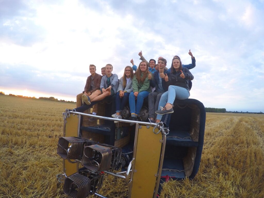groep jongeren geniet van comfortabele ballonvaart met airo in west-vlaanderen en henegouwen op landing