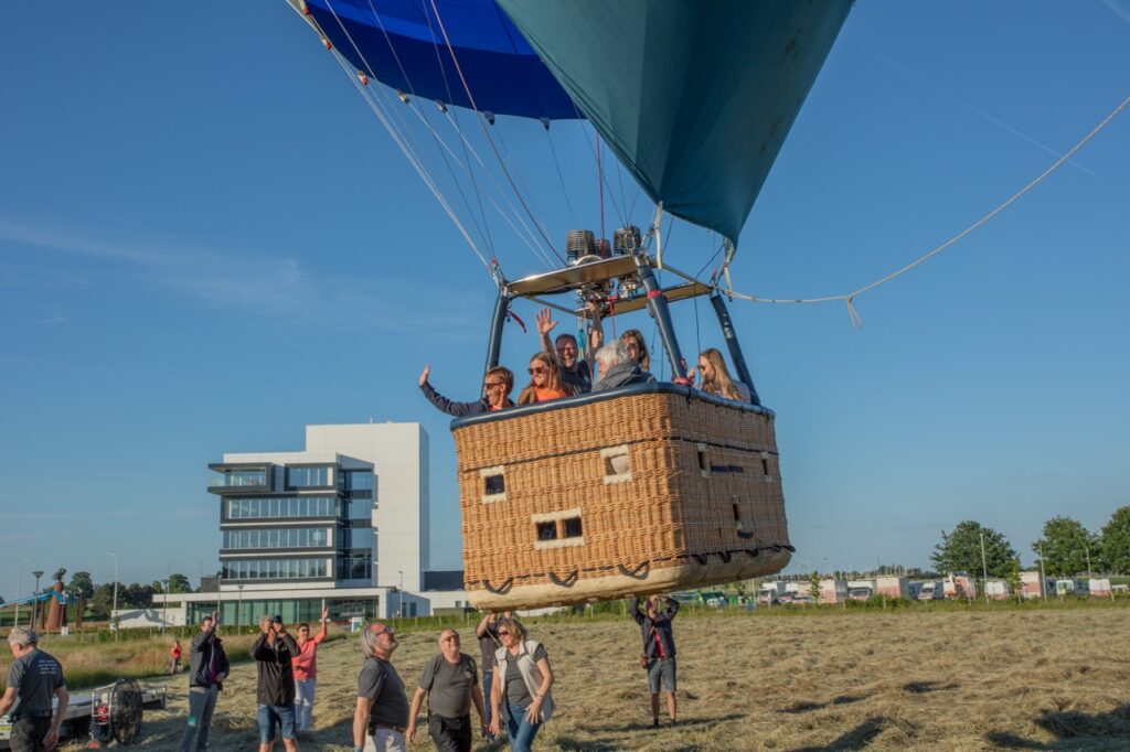 comfortabele ballonvaart met vrolijke passagiers in rieten mand door airo in west-vlaanderen en henegouwen