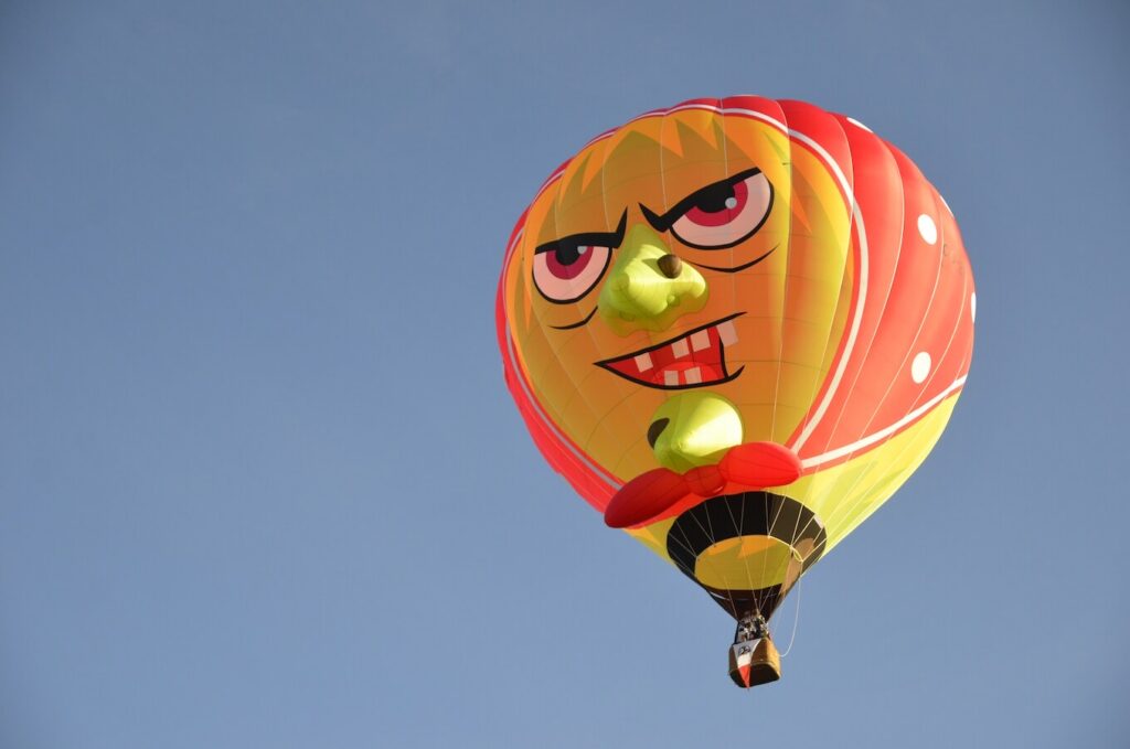 luchtballon met een grote vrolijke clownsgezicht tijdens een ballonvaart van Airo in West-Vlaanderen en Henegouwen